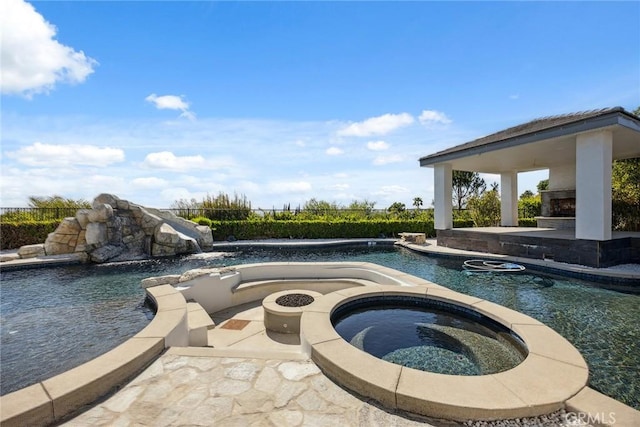 pool featuring a water slide, an outdoor fire pit, an in ground hot tub, and a patio area