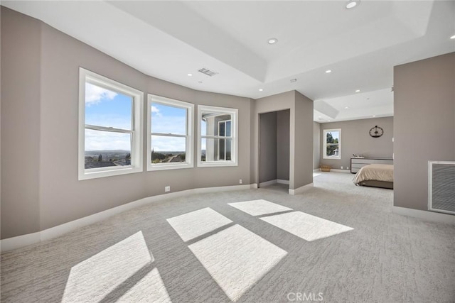 unfurnished bedroom with recessed lighting, visible vents, light colored carpet, and a tray ceiling