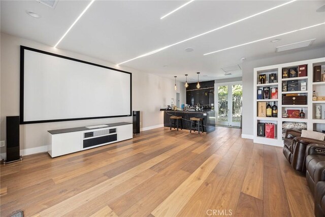 home theater with light wood-style flooring, built in features, and baseboards
