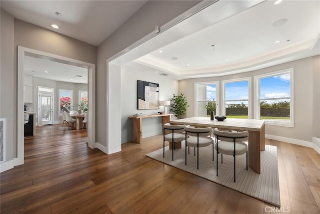 dining area with recessed lighting, a tray ceiling, visible vents, baseboards, and hardwood / wood-style floors