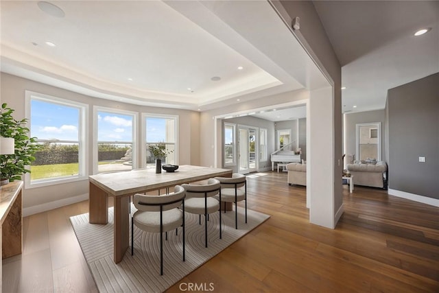 dining room featuring baseboards, recessed lighting, wood finished floors, and a tray ceiling