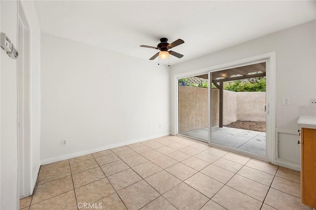 spare room featuring ceiling fan, baseboards, and light tile patterned floors