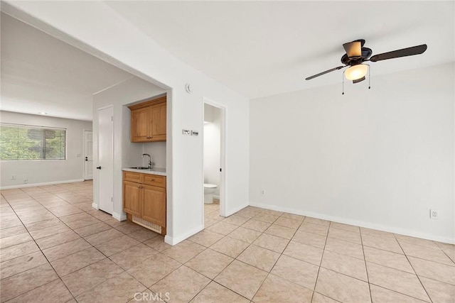 spare room with ceiling fan, baseboards, a sink, and light tile patterned floors