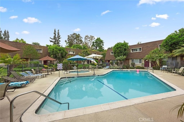 pool with a residential view, a hot tub, a patio, and fence