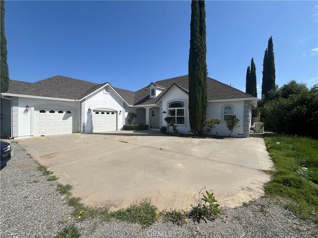 ranch-style house featuring roof with shingles, an attached garage, stucco siding, and driveway