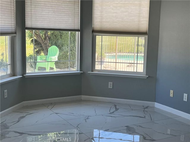 empty room featuring a healthy amount of sunlight and marble finish floor