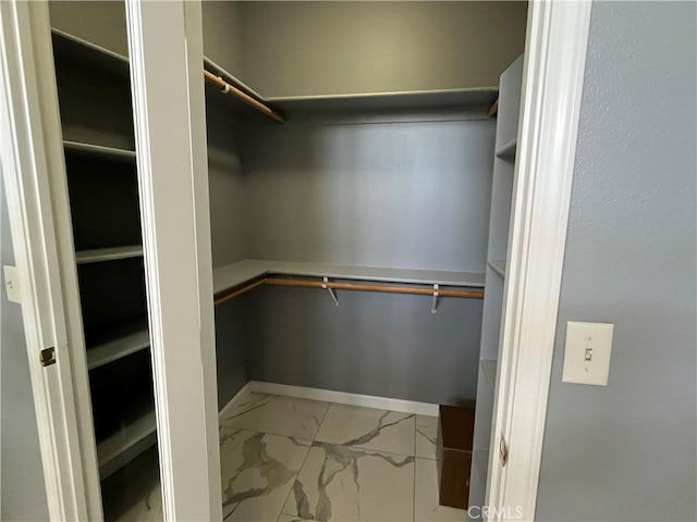 walk in closet featuring marble finish floor