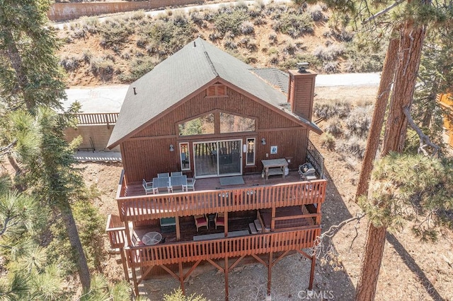 back of house with a chimney, a wooden deck, and outdoor dining area