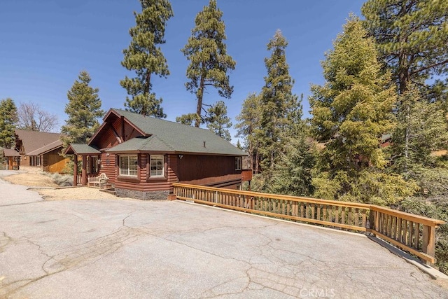 view of side of home featuring aphalt driveway and log siding