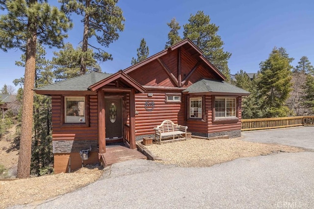 log cabin featuring roof with shingles and log veneer siding