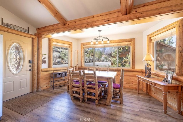 dining area featuring plenty of natural light, vaulted ceiling with beams, and light wood-style flooring