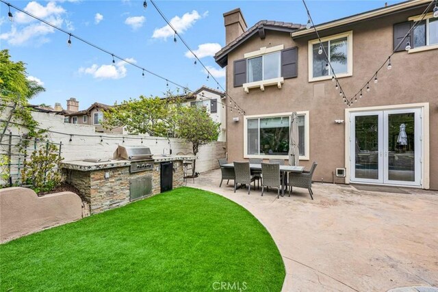 back of property featuring exterior kitchen, a chimney, a fenced backyard, and a patio area