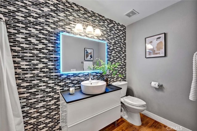 bathroom featuring visible vents, tasteful backsplash, wood finished floors, vanity, and toilet
