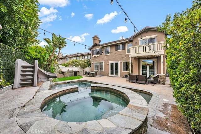 back of property with an in ground hot tub, an outdoor living space, a balcony, french doors, and a patio