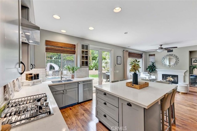 kitchen with decorative backsplash, a glass covered fireplace, recessed lighting, gray cabinets, and appliances with stainless steel finishes