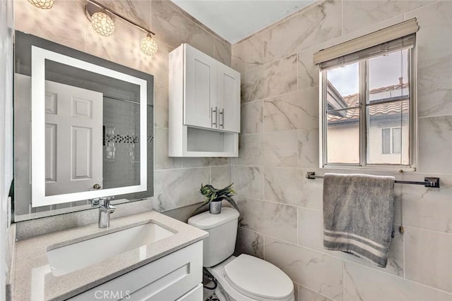 bathroom featuring toilet, tile walls, and vanity
