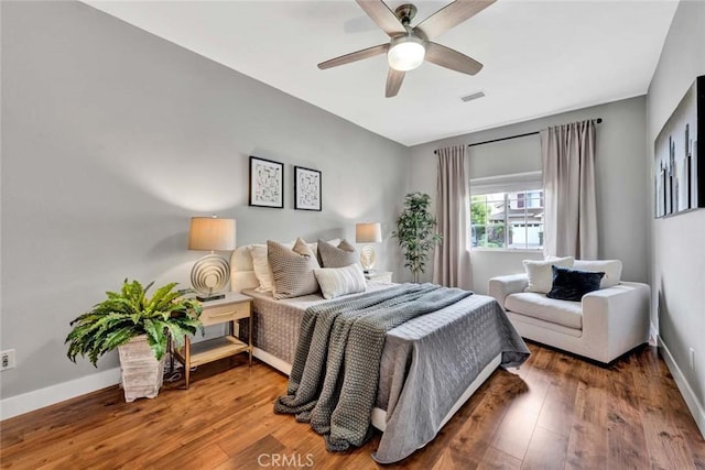 bedroom with baseboards, ceiling fan, wood finished floors, and visible vents