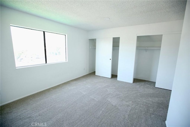 unfurnished bedroom featuring multiple closets, a textured ceiling, and carpet