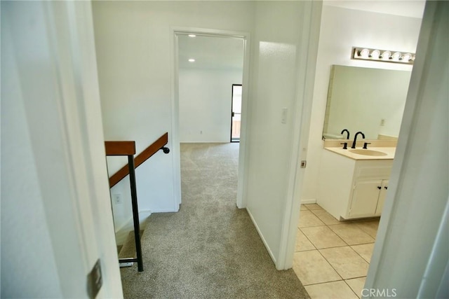 hallway with an upstairs landing, light tile patterned floors, light carpet, and a sink