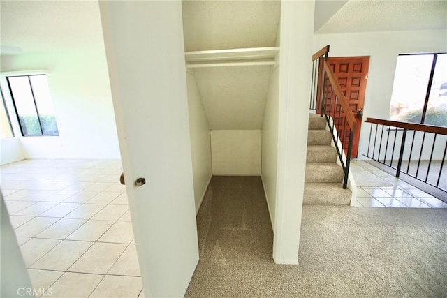 stairway featuring carpet floors, tile patterned flooring, and vaulted ceiling with beams