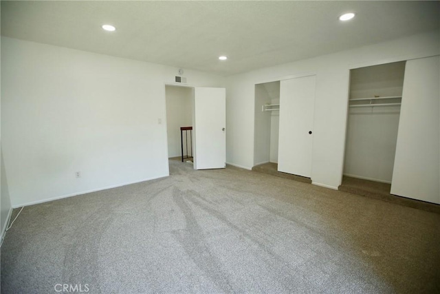 unfurnished bedroom featuring multiple closets, carpet floors, baseboards, visible vents, and recessed lighting