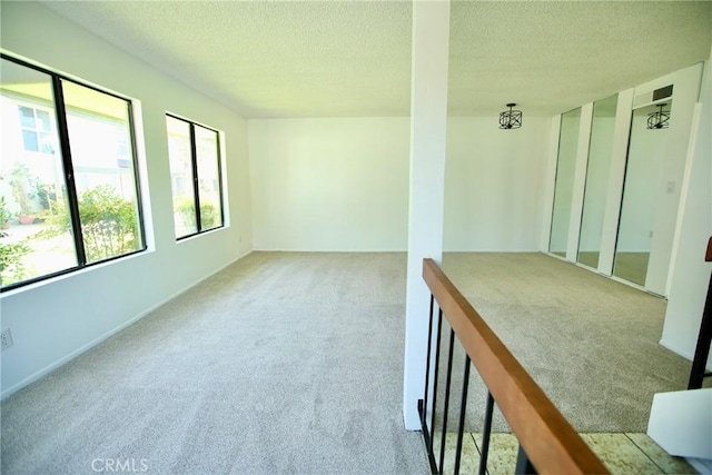 spare room with carpet, a textured ceiling, and baseboards