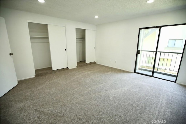 unfurnished bedroom featuring a textured ceiling, multiple closets, carpet, access to exterior, and recessed lighting