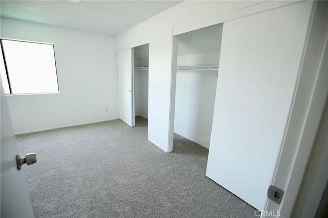 unfurnished bedroom featuring multiple closets, carpet, and a textured ceiling