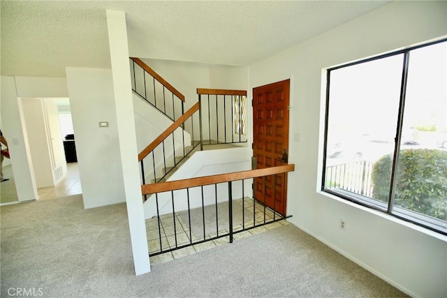 staircase with baseboards, a textured ceiling, and carpet