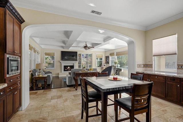 2831 Shenandoah Dr, Chula Vista, CA 91914 - dining space featuring arched walkways, stone tile flooring, a ceiling fan, plenty of natural light, and beamed ceiling