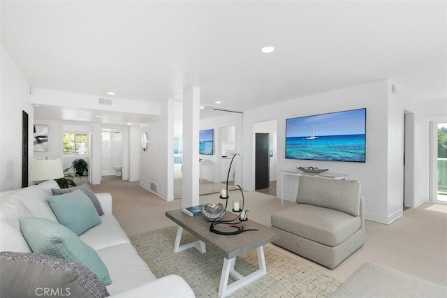 living area featuring recessed lighting, plenty of natural light, and light carpet
