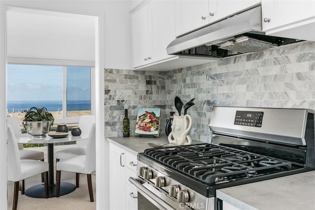 kitchen featuring light countertops, white cabinetry, gas stove, and under cabinet range hood