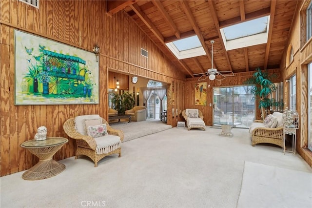 living area with wood walls, a healthy amount of sunlight, carpet floors, and a skylight