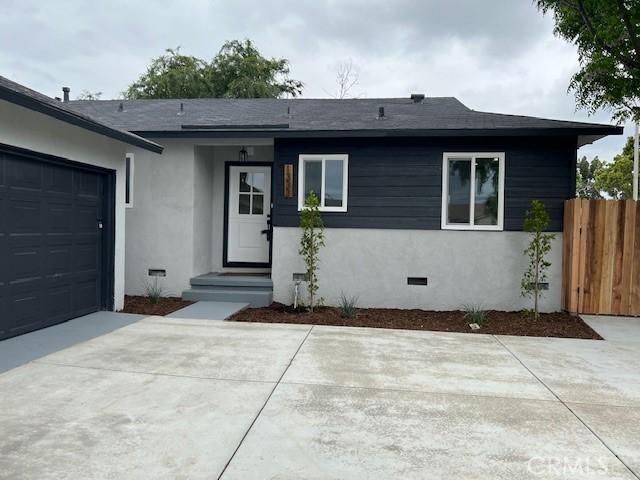 view of front facade with driveway, fence, an attached garage, crawl space, and stucco siding