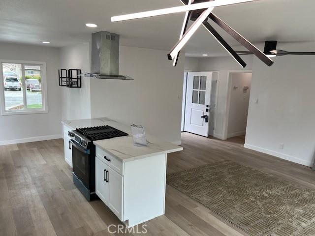 1333 Lancewood Ave, Hacienda Heights, CA 91745 - kitchen with wall chimney range hood, black gas stove, baseboards, white cabinets, and open floor plan
