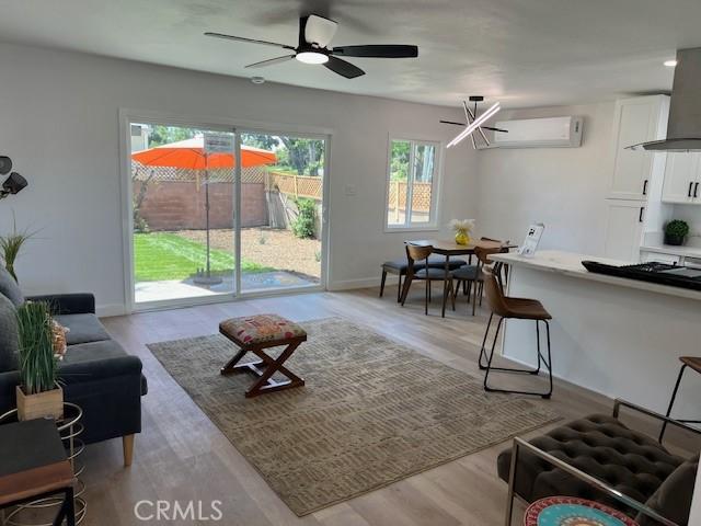 1333 Lancewood Ave, Hacienda Heights, CA 91745 - living room featuring an AC wall unit, light wood finished floors, ceiling fan, and baseboards