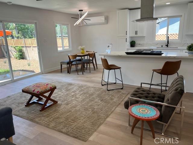 1333 Lancewood Ave, Hacienda Heights, CA 91745 - kitchen featuring wall chimney range hood, a sink, white cabinetry, light countertops, and light wood finished floors