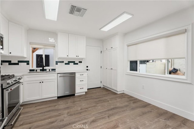 6130 Myrtle Ave, Long Beach, CA 90805 - kitchen with a sink, stainless steel appliances, white cabinetry, decorative backsplash, and visible vents