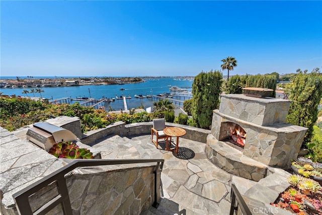 309 Carnation Ave Unit 4, Corona Del Mar, CA 92625 - view of patio / terrace featuring an outdoor stone fireplace, a water view, area for grilling, and a boat dock