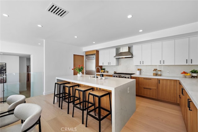 309 Carnation Ave Unit 4, Corona Del Mar, CA 92625 - kitchen featuring wall chimney exhaust hood, high end refrigerator, light wood-style flooring, decorative backsplash, and recessed lighting