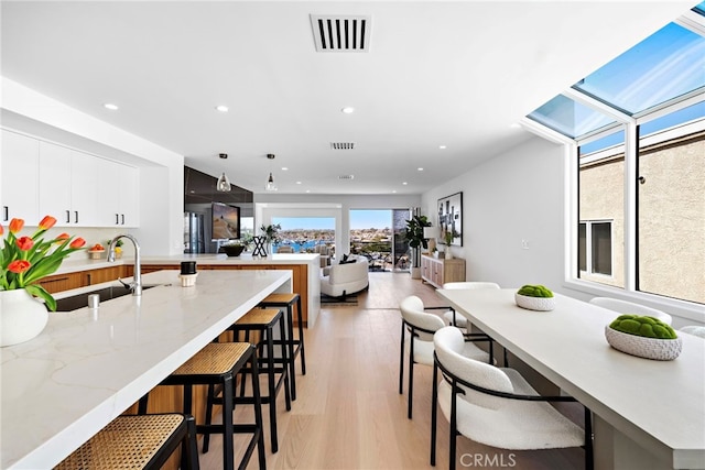 309 Carnation Ave Unit 4, Corona Del Mar, CA 92625 - kitchen with recessed lighting, a breakfast bar, light wood-type flooring, white cabinets, and a peninsula