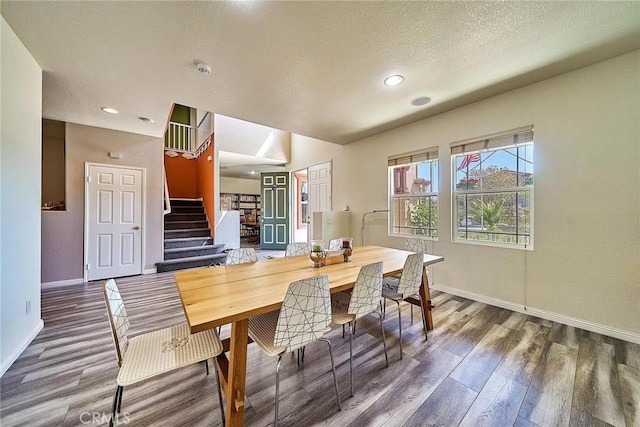 dining area with wood finished floors, baseboards, a textured ceiling, and stairway