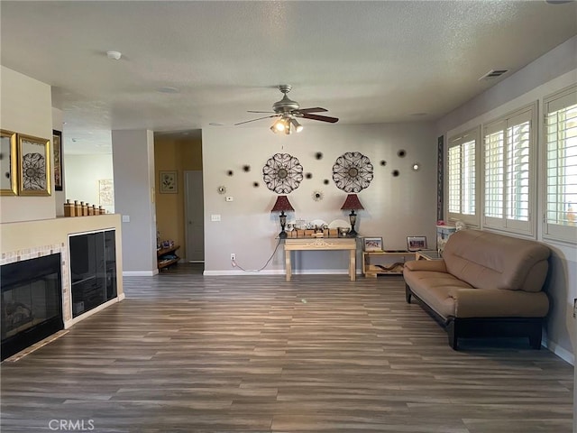 living room featuring wood finished floors, a tile fireplace, visible vents, and ceiling fan