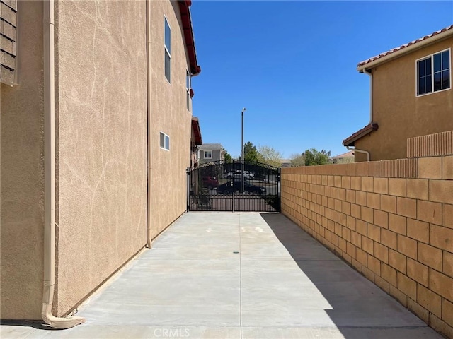view of side of property with a gate, stucco siding, and fence