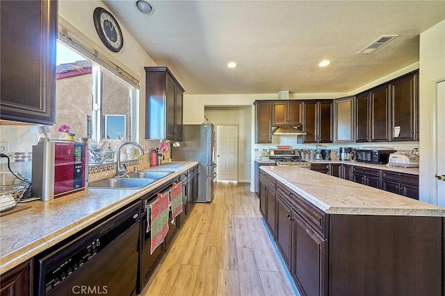 kitchen featuring stainless steel appliances, a center island, a sink, visible vents, and under cabinet range hood