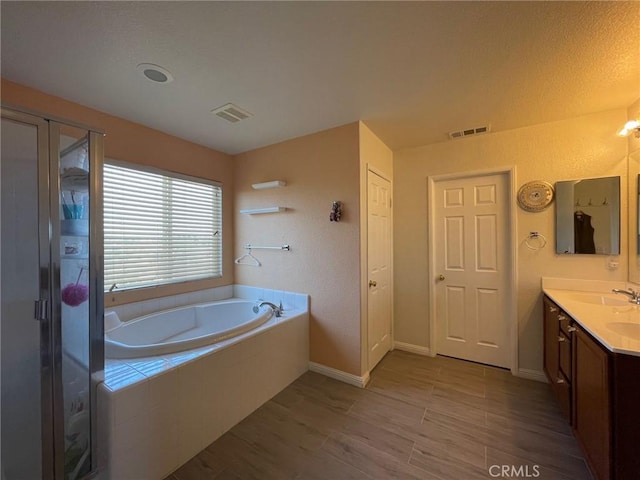 full bathroom featuring a garden tub, wood finished floors, vanity, baseboards, and visible vents