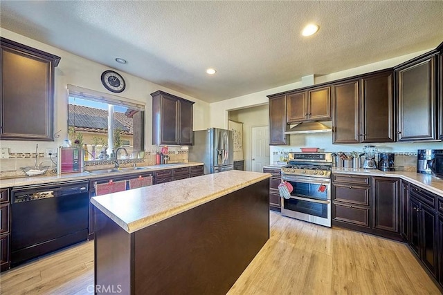 kitchen featuring a sink, light countertops, stainless steel appliances, light wood-style flooring, and under cabinet range hood