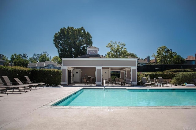 community pool with fence and a patio area