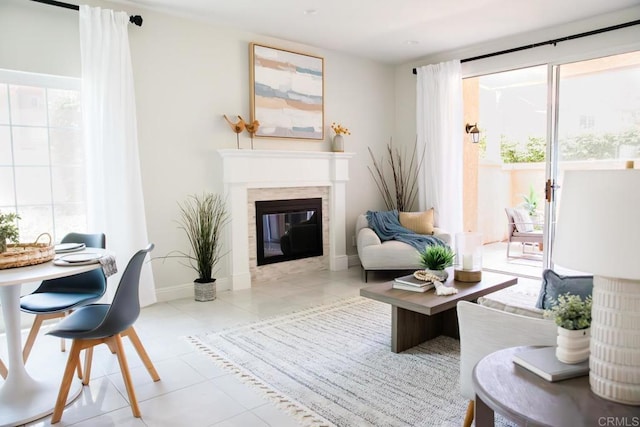 sitting room with baseboards, a glass covered fireplace, and tile patterned flooring