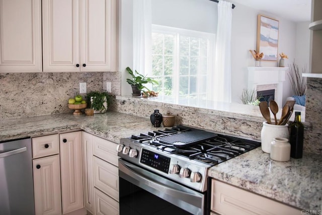 kitchen with appliances with stainless steel finishes, tasteful backsplash, light stone counters, and a fireplace